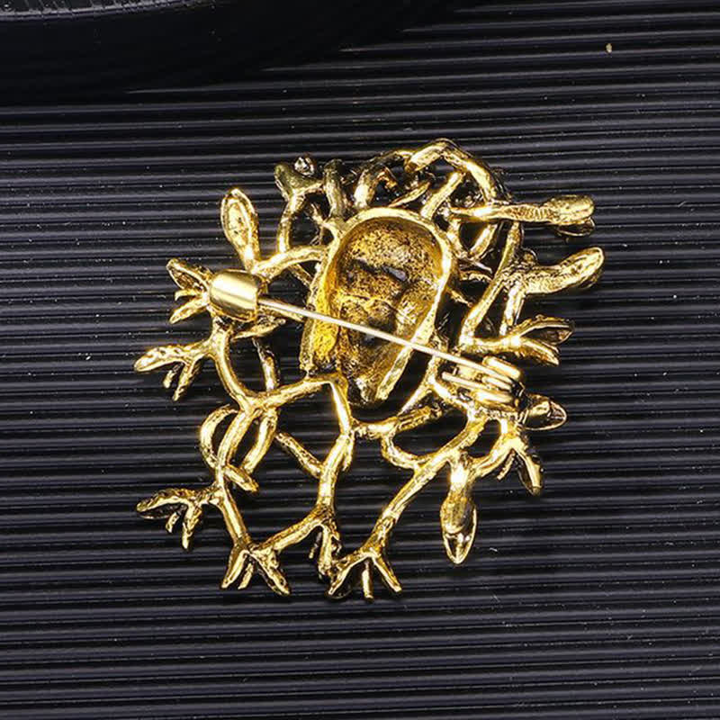 Broche tête de mort exagérée enveloppée de serpent