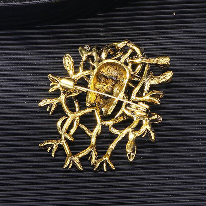 Broche tête de mort exagérée enveloppée de serpent